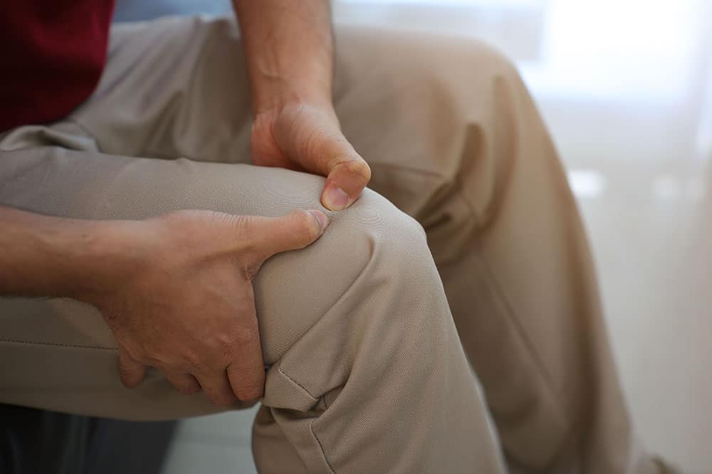 Mature man holding his leg above the knee after knee surgery