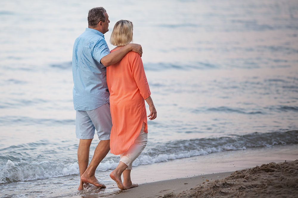 Middle aged couple enjoying a walk on the beach