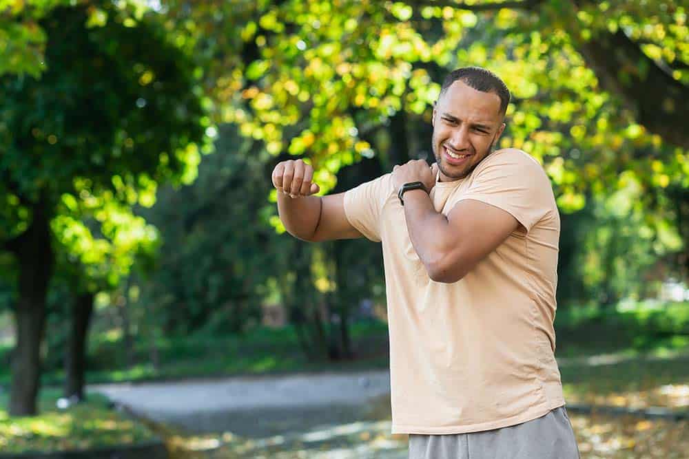 Middle aged man on a walking path with stiffness and soreness in his shoulder after surgery